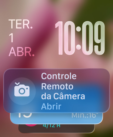 O widget Controle Remoto da Câmera aparece na parte inferior da tela, números das horas translúcidos no canto superior direito e data no canto superior esquerdo.