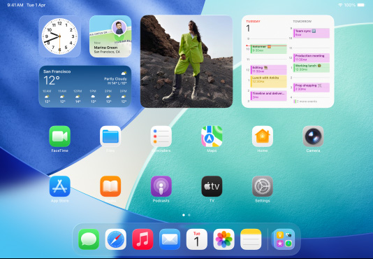 iPad, three models, landscape orientation, with centre model in front of two others, Apple Pencil magnetically attached to top of centre model, centre screen showing the Home Screen featuring colourful app icons with Liquid Glass effect, left screen showing the Preview app, right screen showing Home Screen with files fanning out from the dock