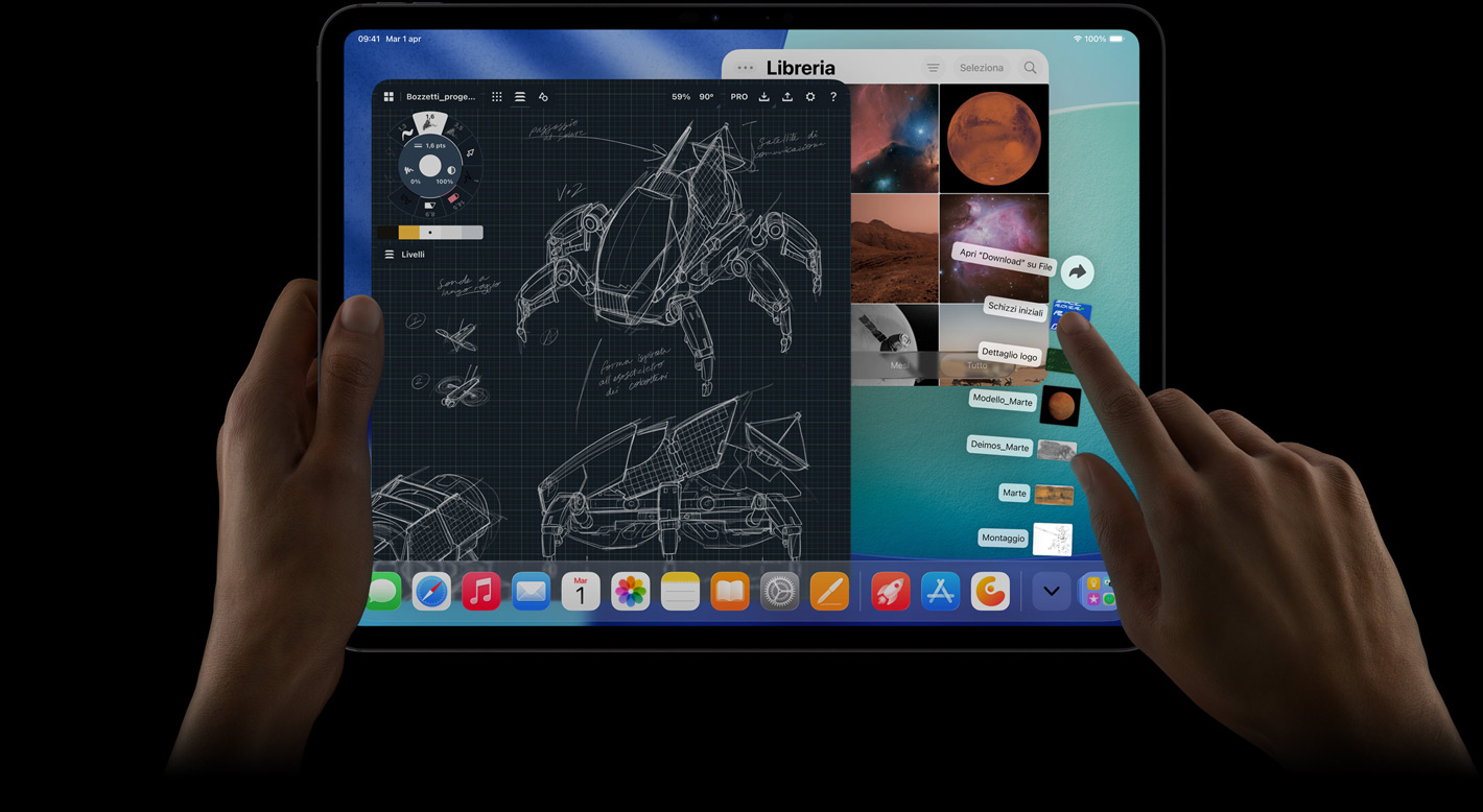 Un iPad Pro in orizzontale, mostrato di fronte, con una mano destra che compie un gesto sopra una serie di file nella cartella Download disposti a ventaglio, il display mostra l’interfaccia di iPadOS 26 con diverse app aperte, tra cui un’app di fotoritocco con progetti dettagliati di robot, annotazioni scritte a mano e varie fasi di progettazione, e la Libreria Foto