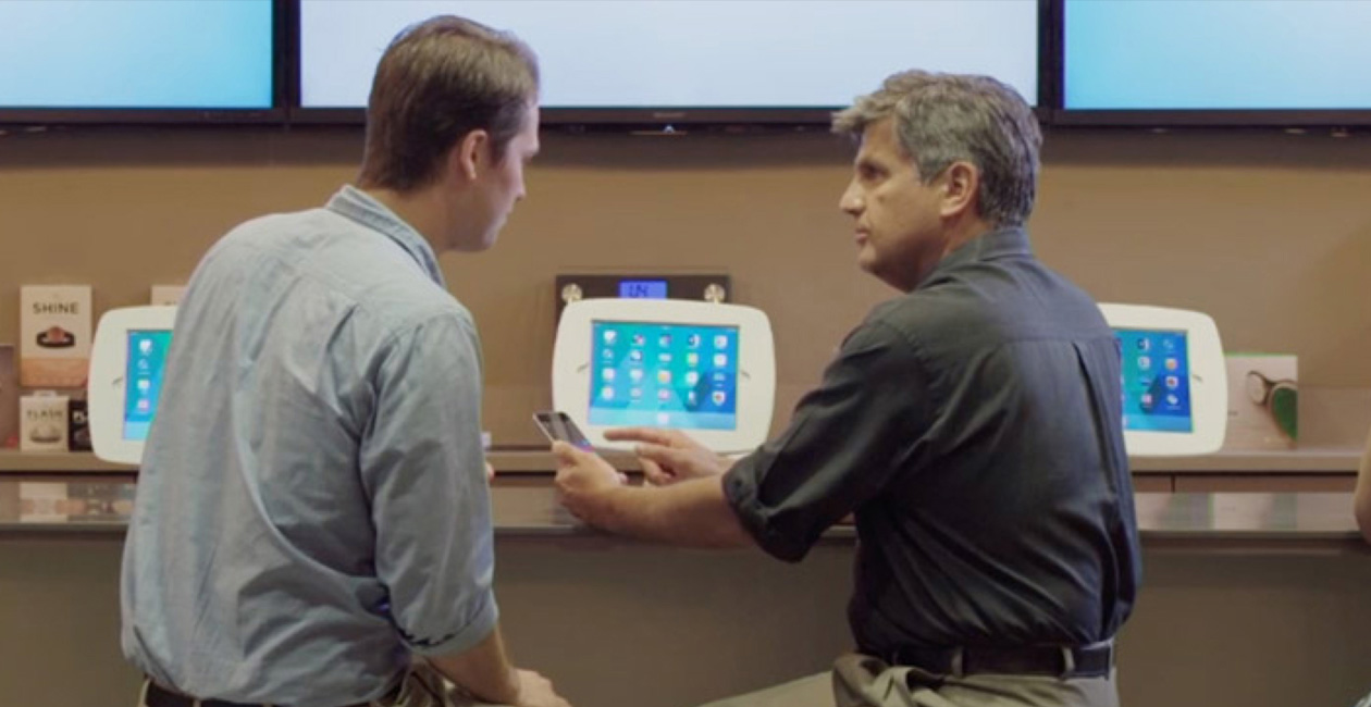 رجلان يجلسان أمام O&nbsp;Bar وينظران إلى شاشة iPhone.‏